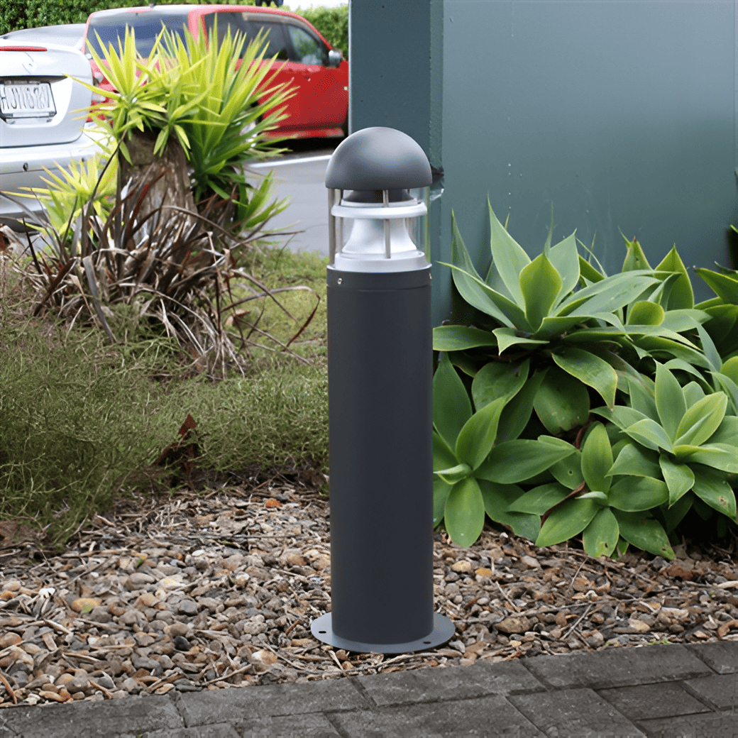 Image of a Dark Grey Vaden Bollard in a garden beside a pathway in a commercial space