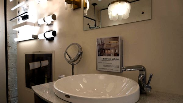 a shot of someof the vanity lights in our showroom, in the reflection in the mirror you can see a chandelier hanging in the same space