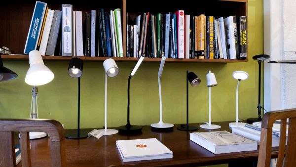 a selection of LED desk lamps on a table with catalogues one the shelf from our showroom